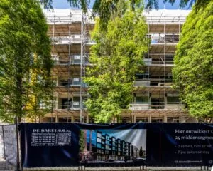 Appartementencomplex aan de Karel du Jardinstraat in Amsterdam in de steigers met bouwdoek waarop het nieuwbouwproject 'De Karel 2.0' wordt aangekondigd.